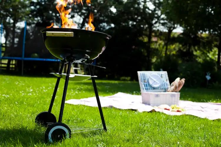 An outdoor grill with fire standing on the grass