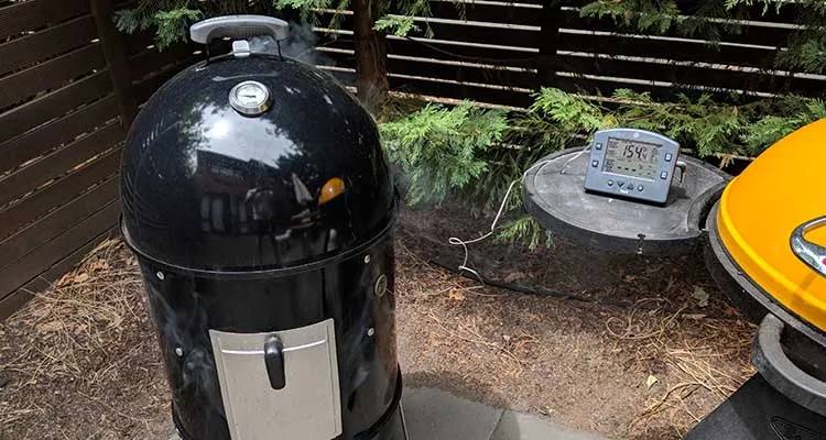 Charcoal smoker with a closed lin and a leave-in meat thermometer