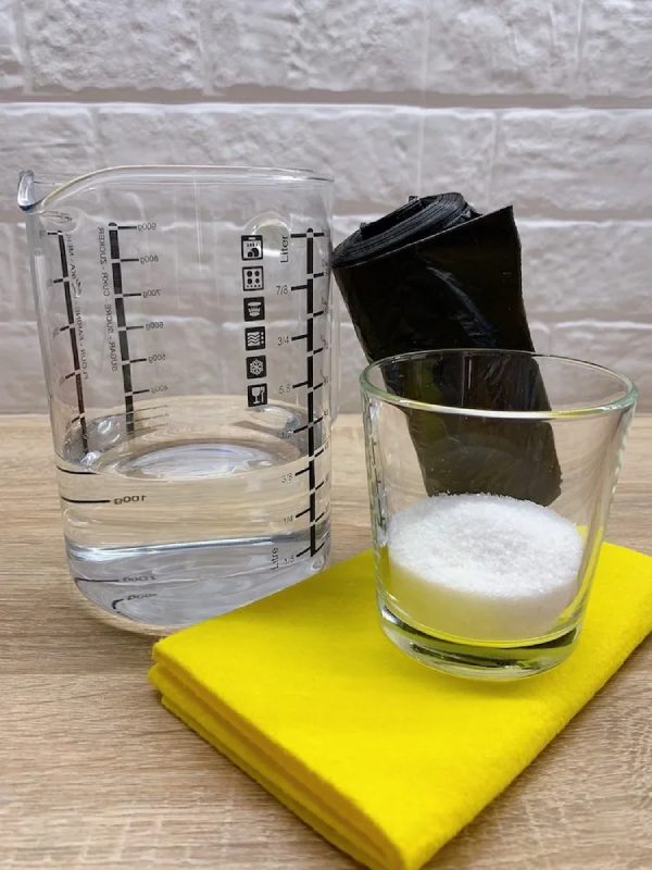 Vinegar, salt, disposable cloth and garbage bag on a wooden table